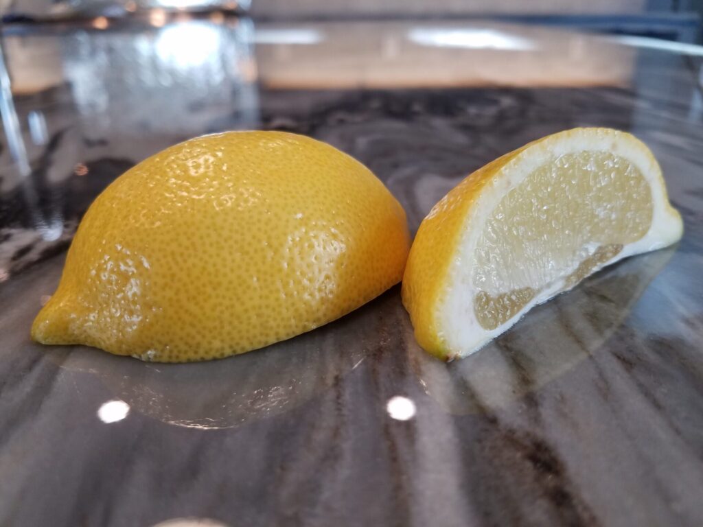 Acidic lemon wedge laying on marble countertops